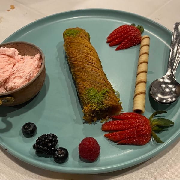 Turkish dessert with shredded pastry, pistachio, strawberry, berries, wafer, and pink ice cream.